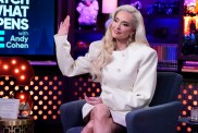 Erika Jayne in a white dress raising her right hand on Watch What Happens Live