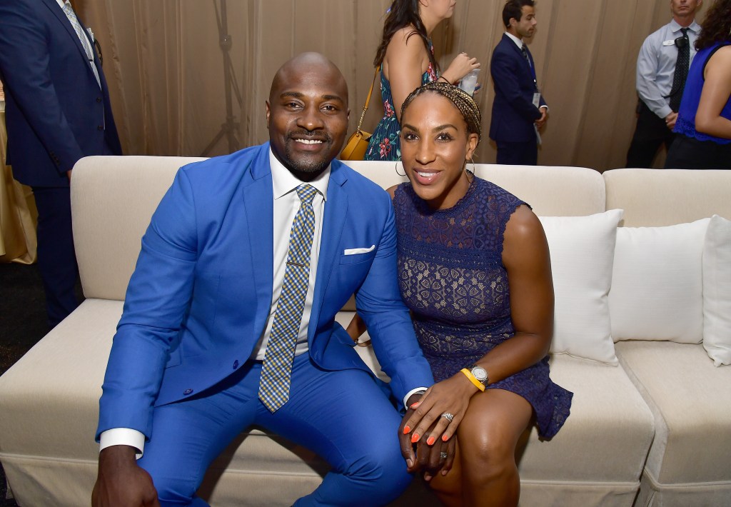 Marcellus Wiley in a blue suit sitting on a couch with wife Annemarie Wiley