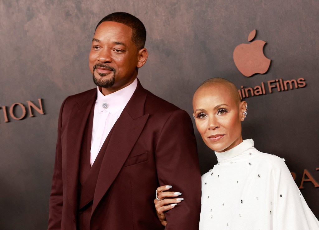 Will Smith in a red suit posing with Jada Pinkett Smith in white