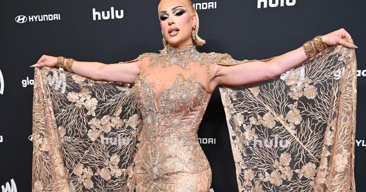 Plane Jane at the GLAAD Media Awards holding out a golden cape