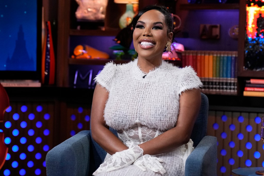 Kelli Ferrell in a white dress with her hands on her lap on Watch What Happens Live