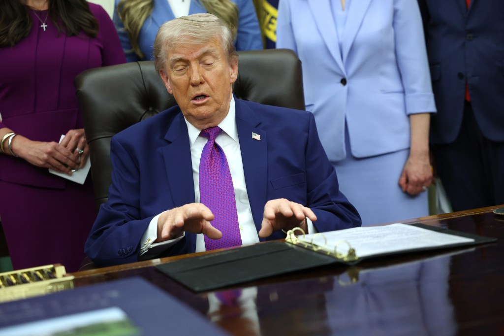 Donald Trump with his hands overing over a binder
