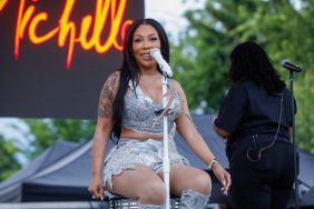 K. MIchelle in a silver two piece sitting on stage at the Spider Anderson Festival