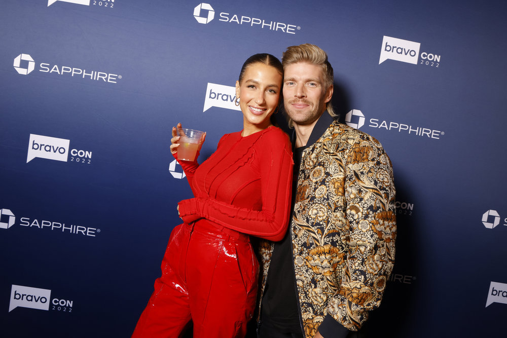 Amanda Batula holding a drink and posing with Kyle Cooke at BravoCon 2022