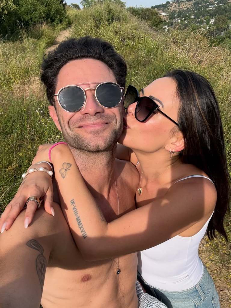 Sasha Farber and Janel Parrish kissing him on the cheek