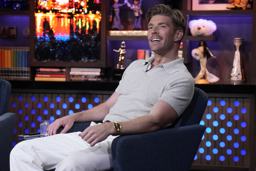Kyle Cooke wearing white and leaning back into this chair on Watch What Happens Live