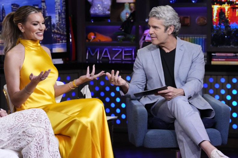Lindsay Hubbard in a yellow dress in the Watch What Happens Live clubhouse with her hands out, facing Andy Cohen