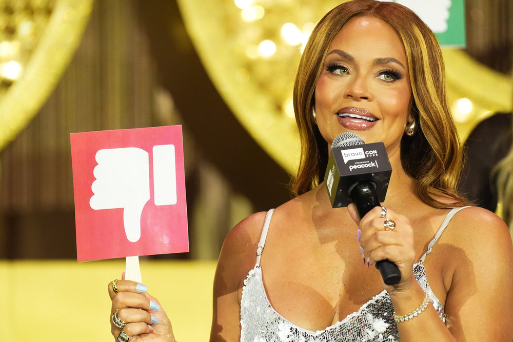 Gizelle Bryant at BravoCon holding a sign with a thumbs down 